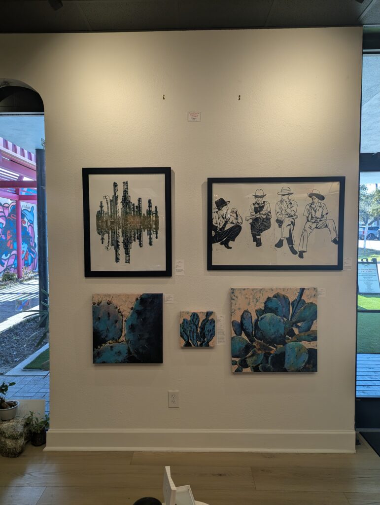 "Emerald City" linocut print by Artist Leslie Deil hanging in the Art For The People Gallery in Austin, TX in February 2026. Also picture is "The Sharecroppers" by Leslie Deil.